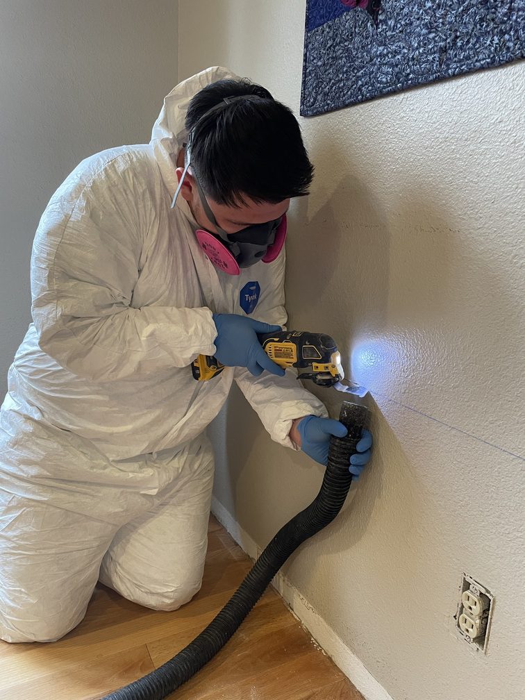 24-7 Restoration team member sawing into drywall while using a vacuum