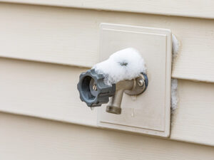 Outdoor water spigot covering in snow during winter.