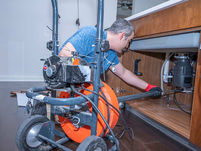Plumber drain cleaning on kitchen sink with rooter