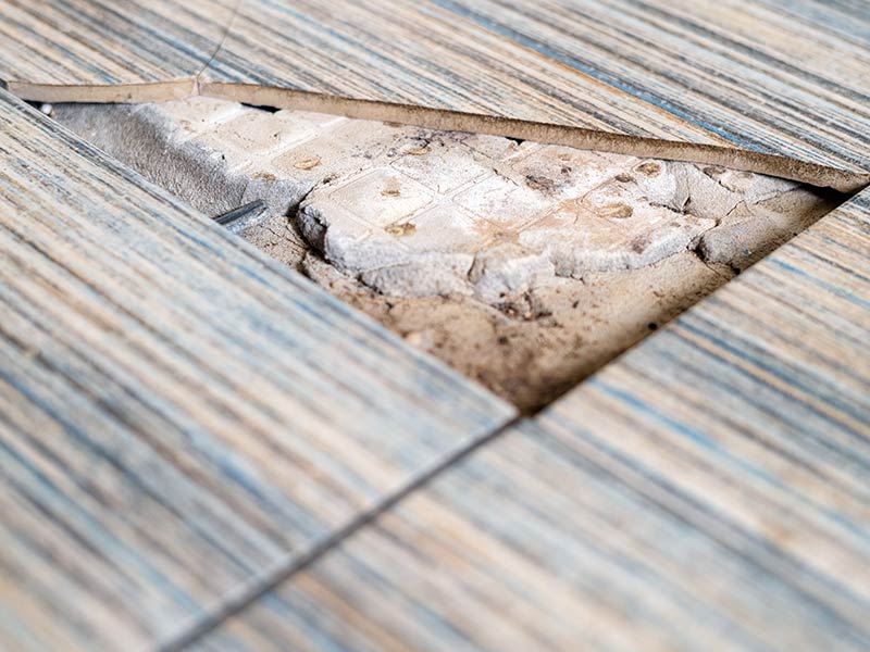 Close up view of broken tile in the bathroom, revealing asbestos
