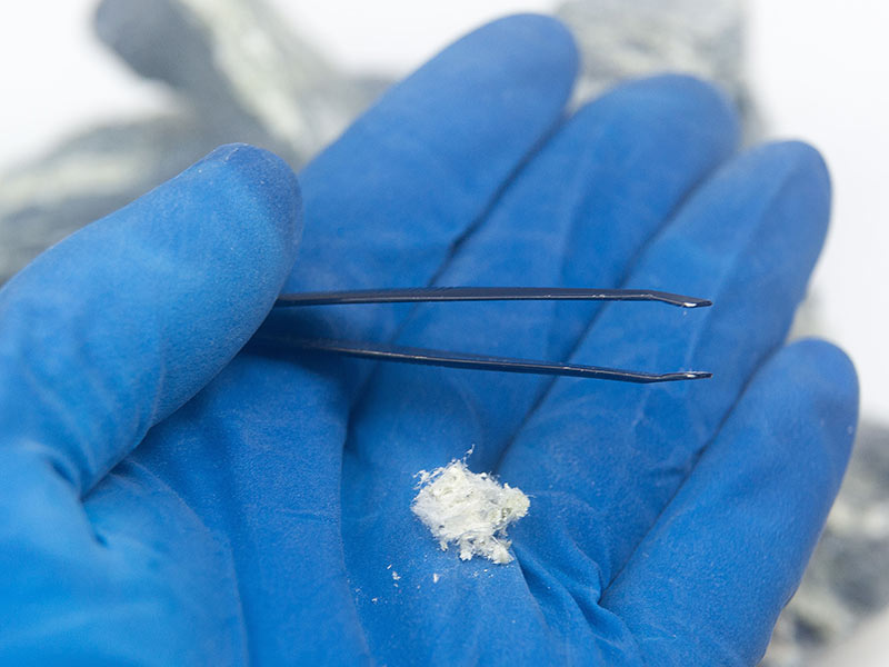 Chrysotile asbestos fibers close-up on hand of a restoration man in gloves