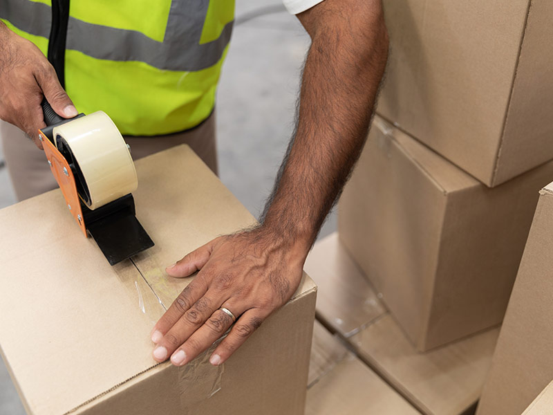packing cardboard box with tape gun dispenser