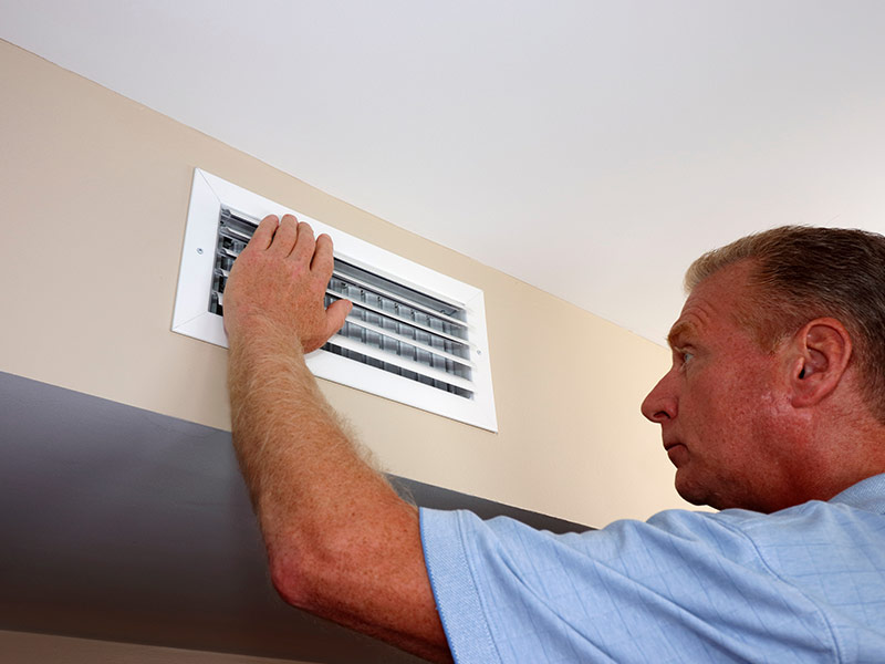 Left Hand of a Man Placed on a Ceiling Air Vent in a Home