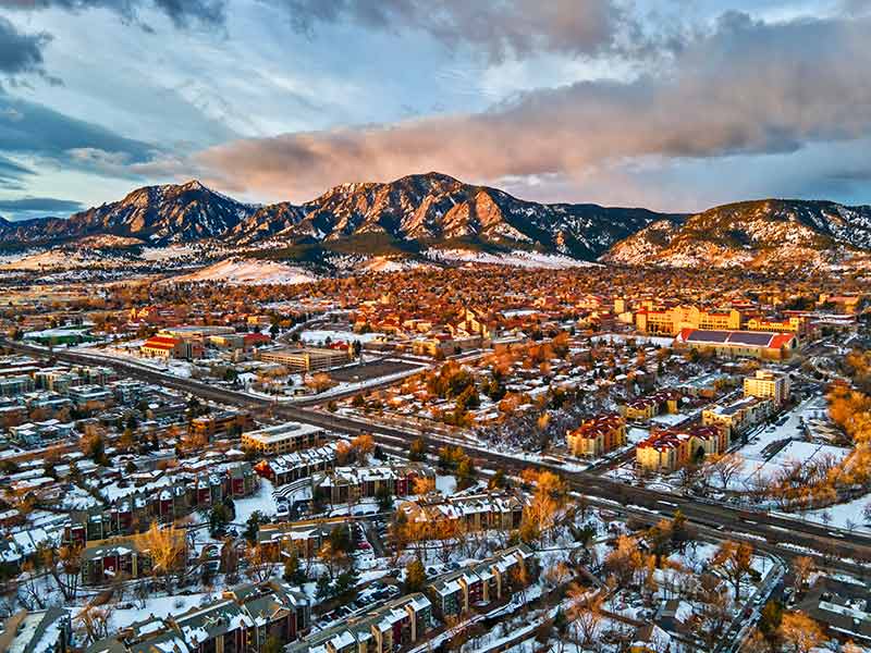 Drone view of Boulder and the Flatirons at sunrise in the winter snow