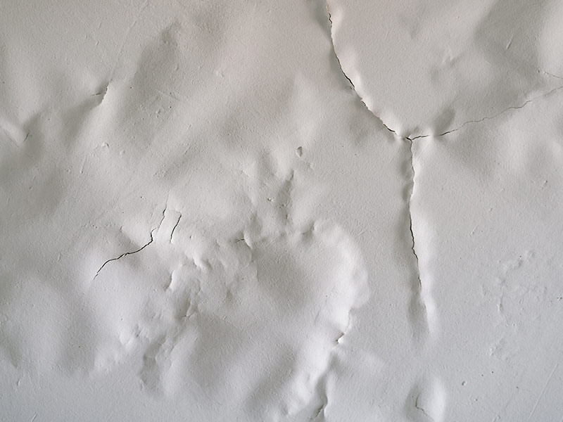 White paint swollen, bubbling from moisture on the ceiling close-up