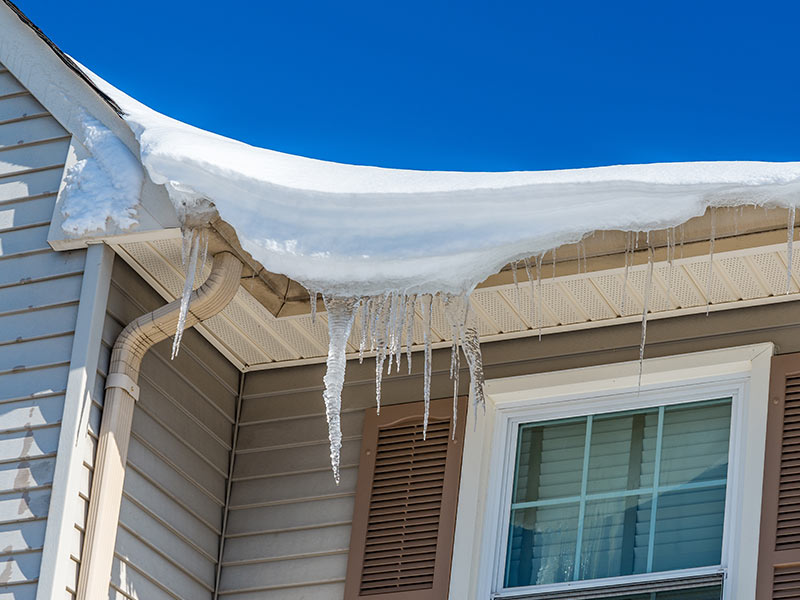 heavy snow and ice buildup on roof of house