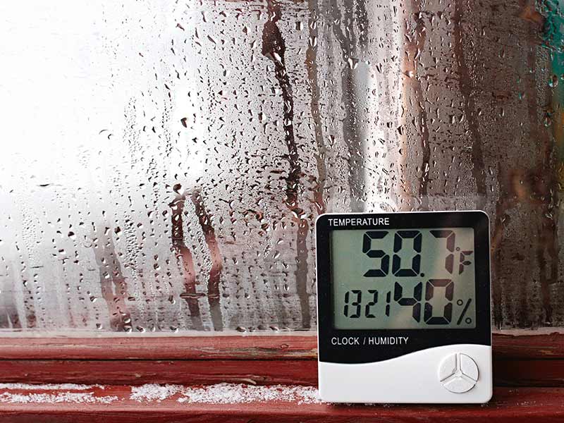 Humidity meter near a window covered in condensation