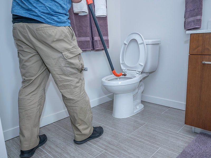 Man using an auger on a toilet