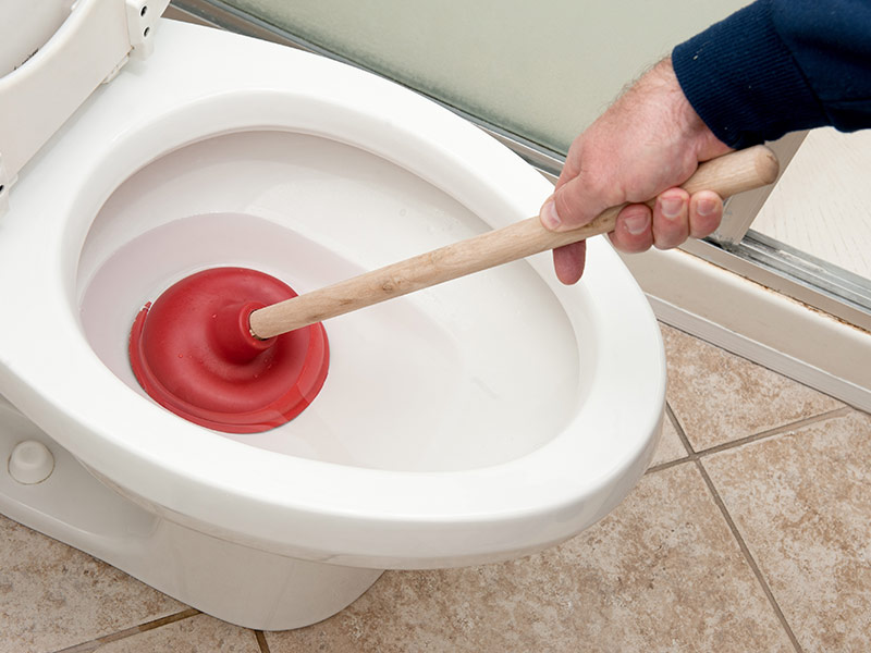 Plumber uncloging toilet using a tight seal
