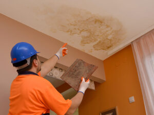 restoration worker points to the place where the leaked water, holding the broken roof tile