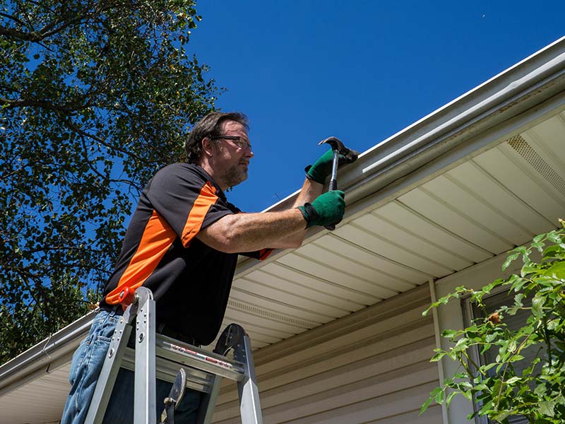home owner repairing a loose gutter