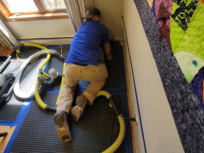 restoration worker restoring a bedroom damaged by water after a storm