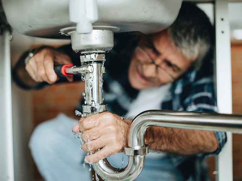 home owner tightening kitchen sink pipe
